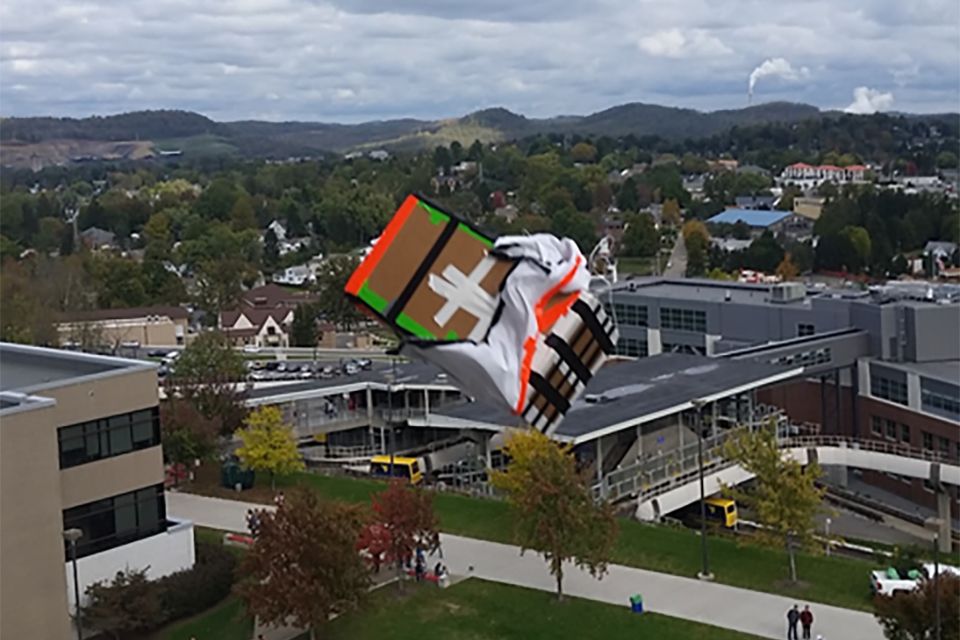 A pumpkin plunges from the roof of the Engineering Sciences building in a cardboard box.